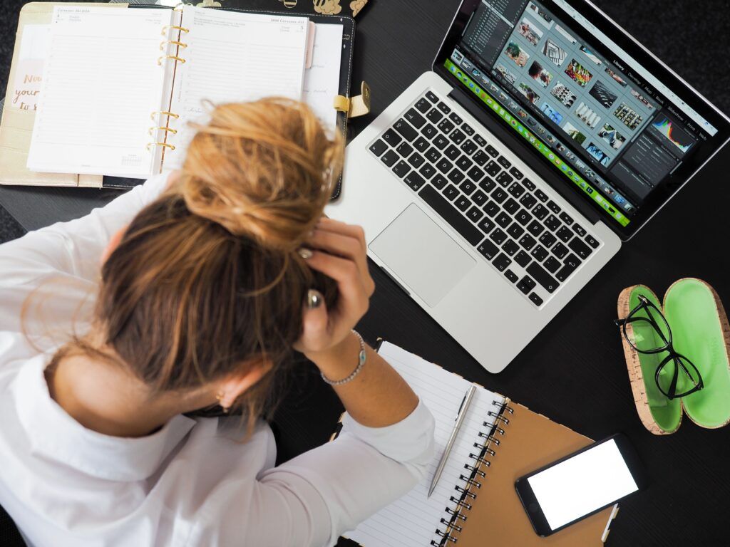 Person feeling overwhelmed at a desk, illustrating the window of tolerance and nervous system stress.