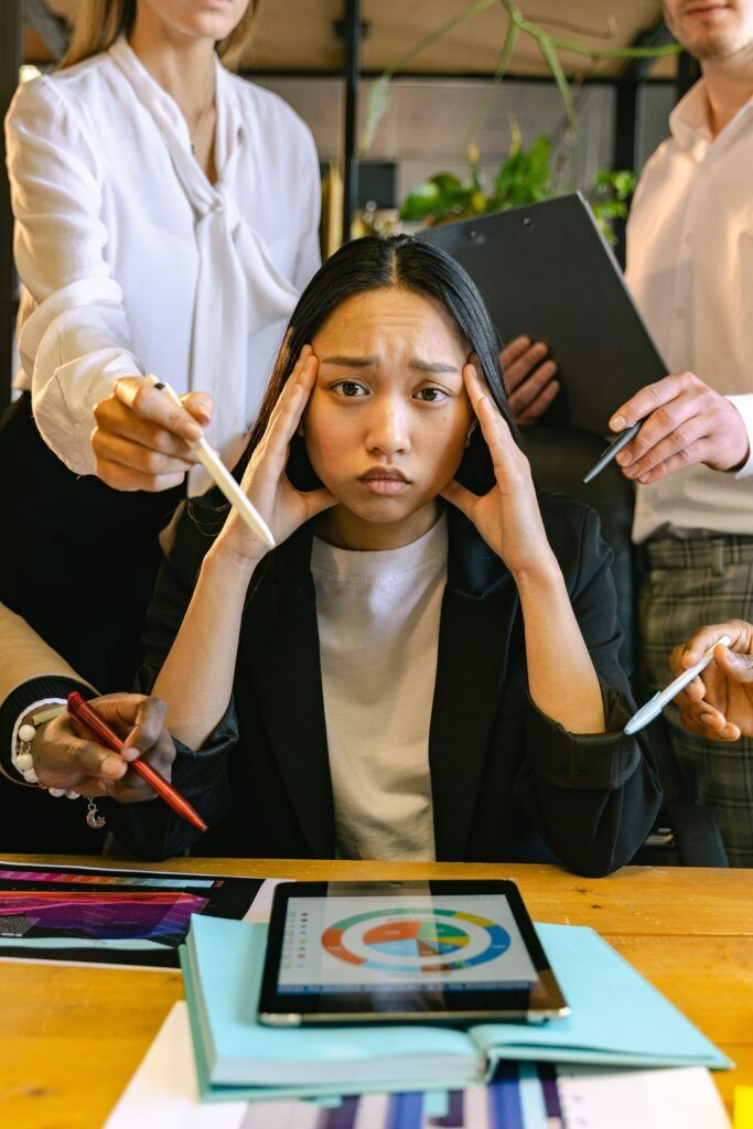 Woman experiencing workplace overwhelm, illustrating the connection between trauma and stress and their effects on emotional wellbeing.